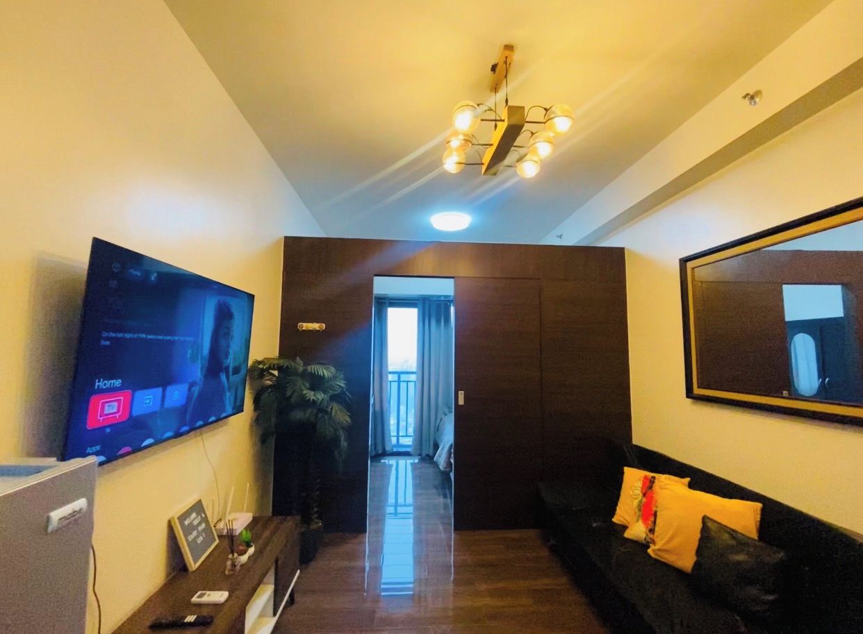 A modern living room with a flat-screen TV, a sofa, a coffee table, and a large mirror.