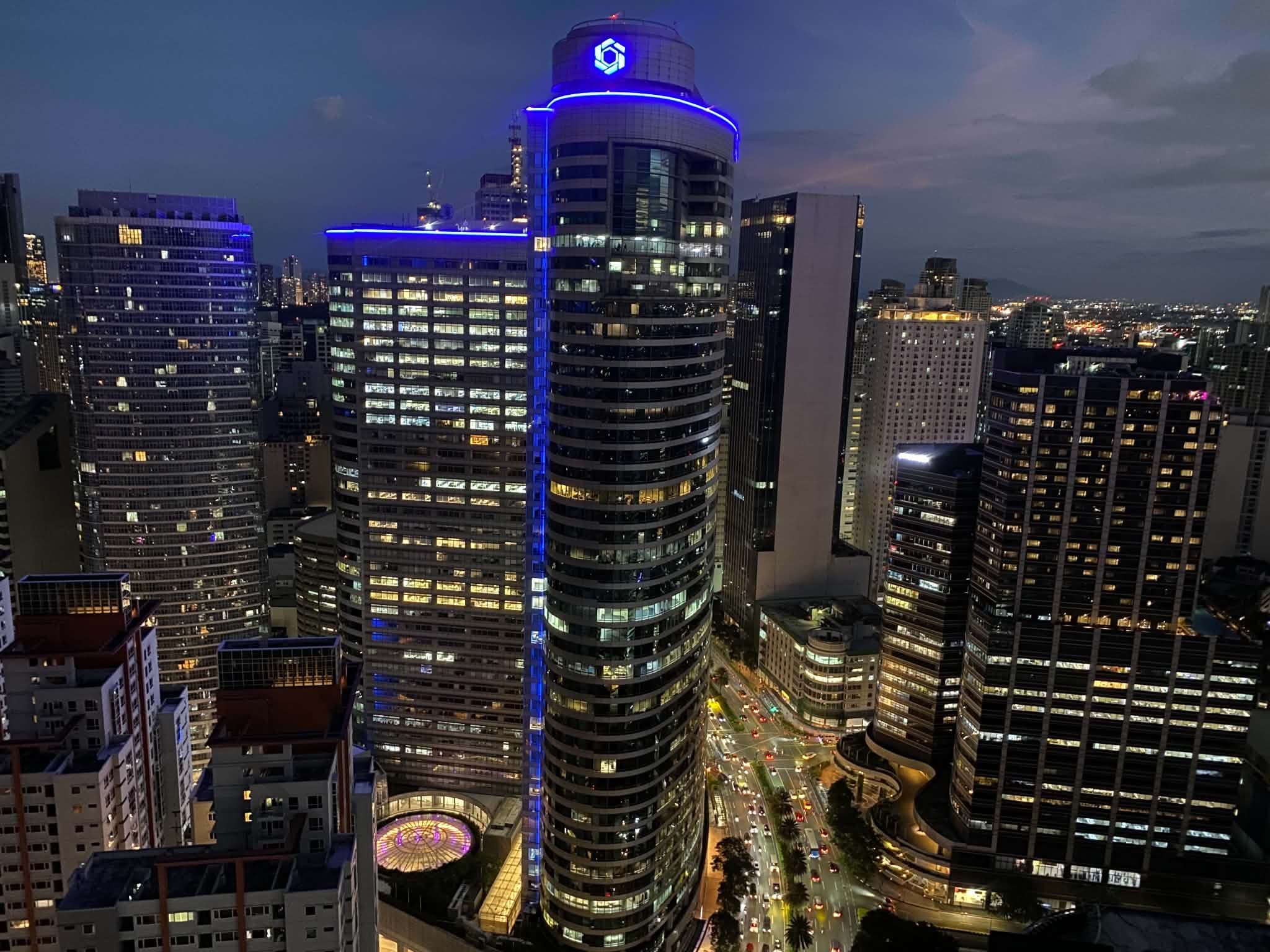 A cityscape at night with illuminated buildings and a busy street.