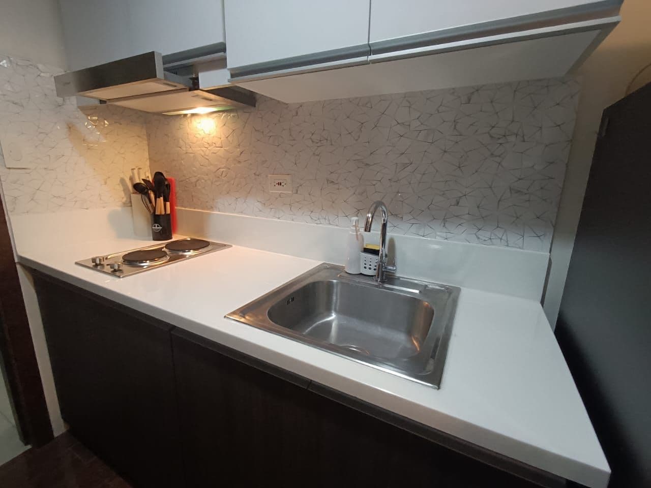 Una cocina con un lavamanos de acero inoxidable, estufa y salpicadero con diseño agrietado.