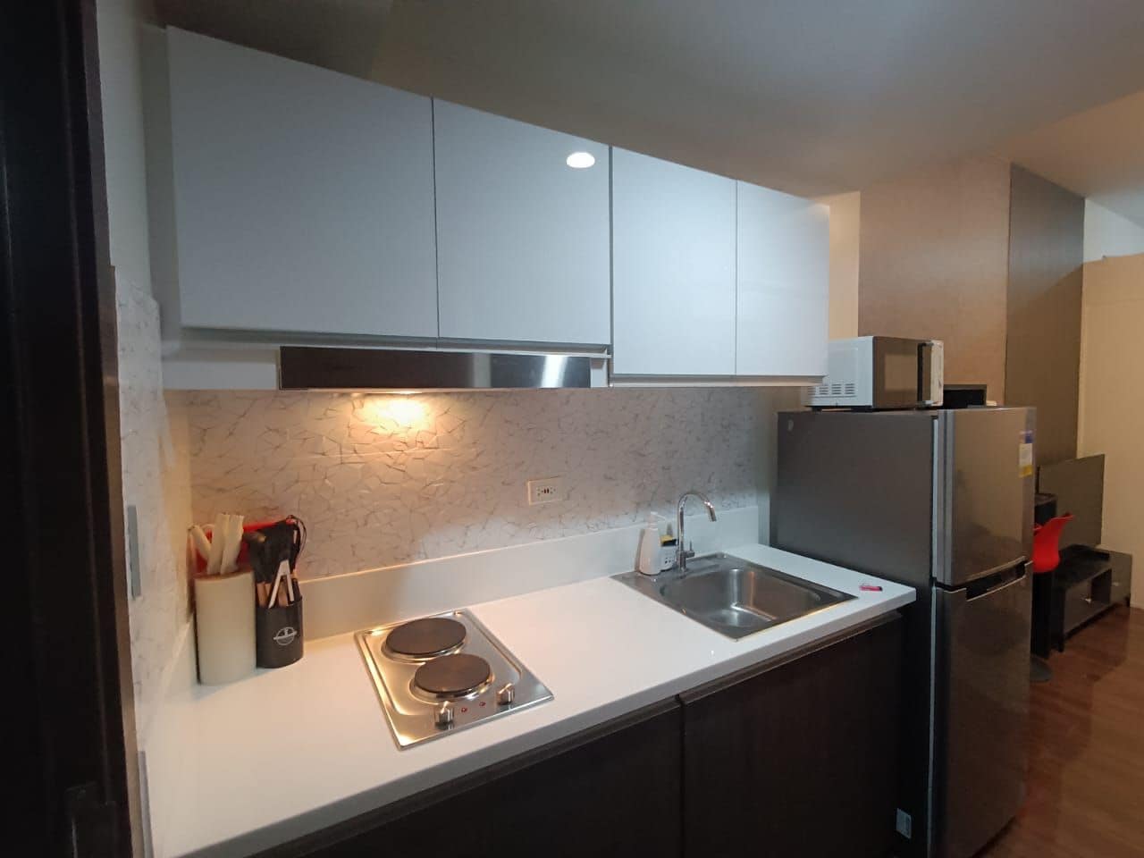A modern kitchen with stainless steel appliances, a white countertop, and dark cabinetry.
