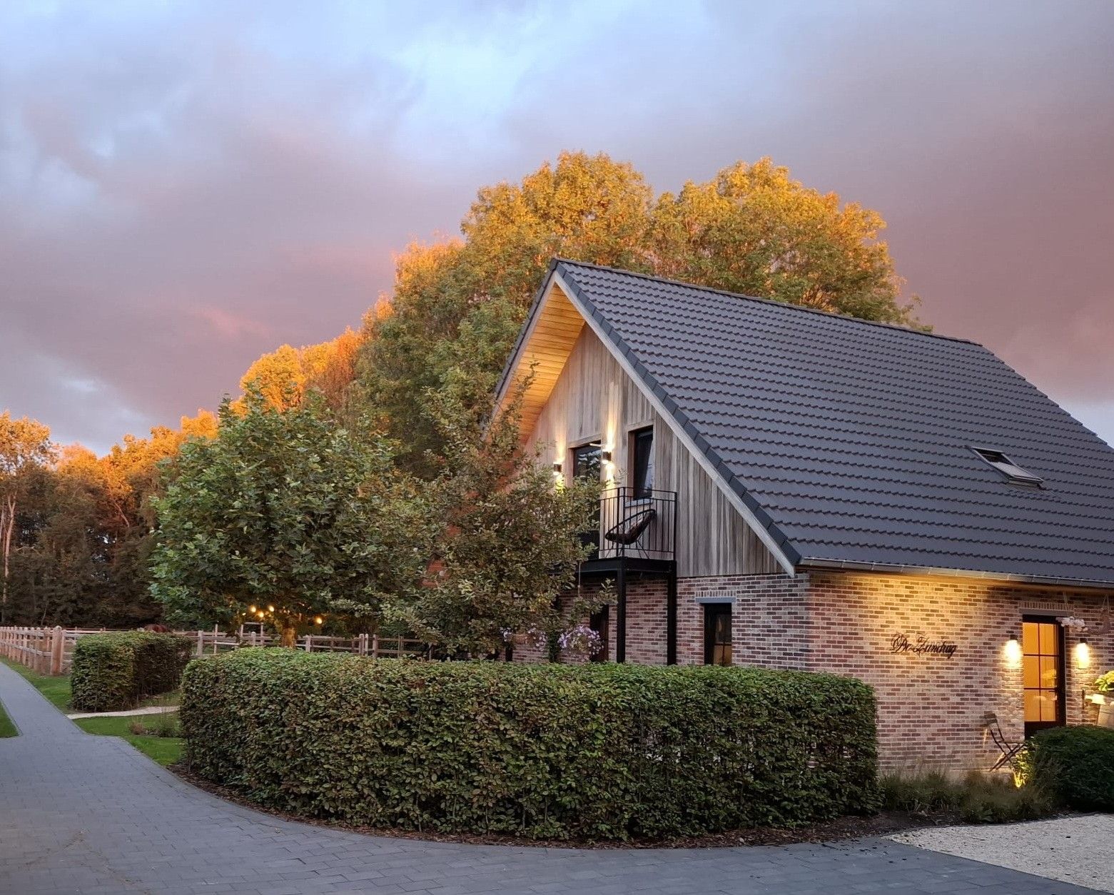 A brick building with a sloped roof, a balcony, and a pathway leading to it.