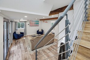 Ein modernes Wohnzimmer mit Treppe, einem großen Gemälde und Blick ins Freie.