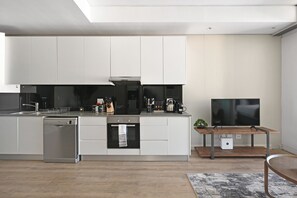 A modern kitchen with a dishwasher, oven, and a flat-screen TV on a wooden table. - Scenic 1BR Retreat Mountain & City Views in vibrant Cape Town (Cape Town)