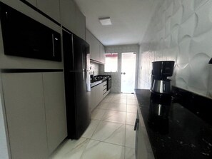 A kitchen with a refrigerator, stove, and coffee maker. - Cj21MSII-3D Porto Seguro - Piscinas/Sauna/Conforto (Porto Seguro)