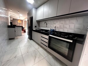 Una cucina moderna con forno integrato, un piano di lavoro nero e una parete di fondo decorata.