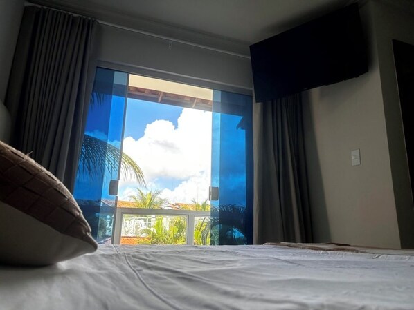 Una camera d'albergo con un letto, tende, una finestra e vista sull'esterno.