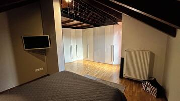 Un dormitorio con cama, televisión, radiador y una escalera que lleva a otra habitación.