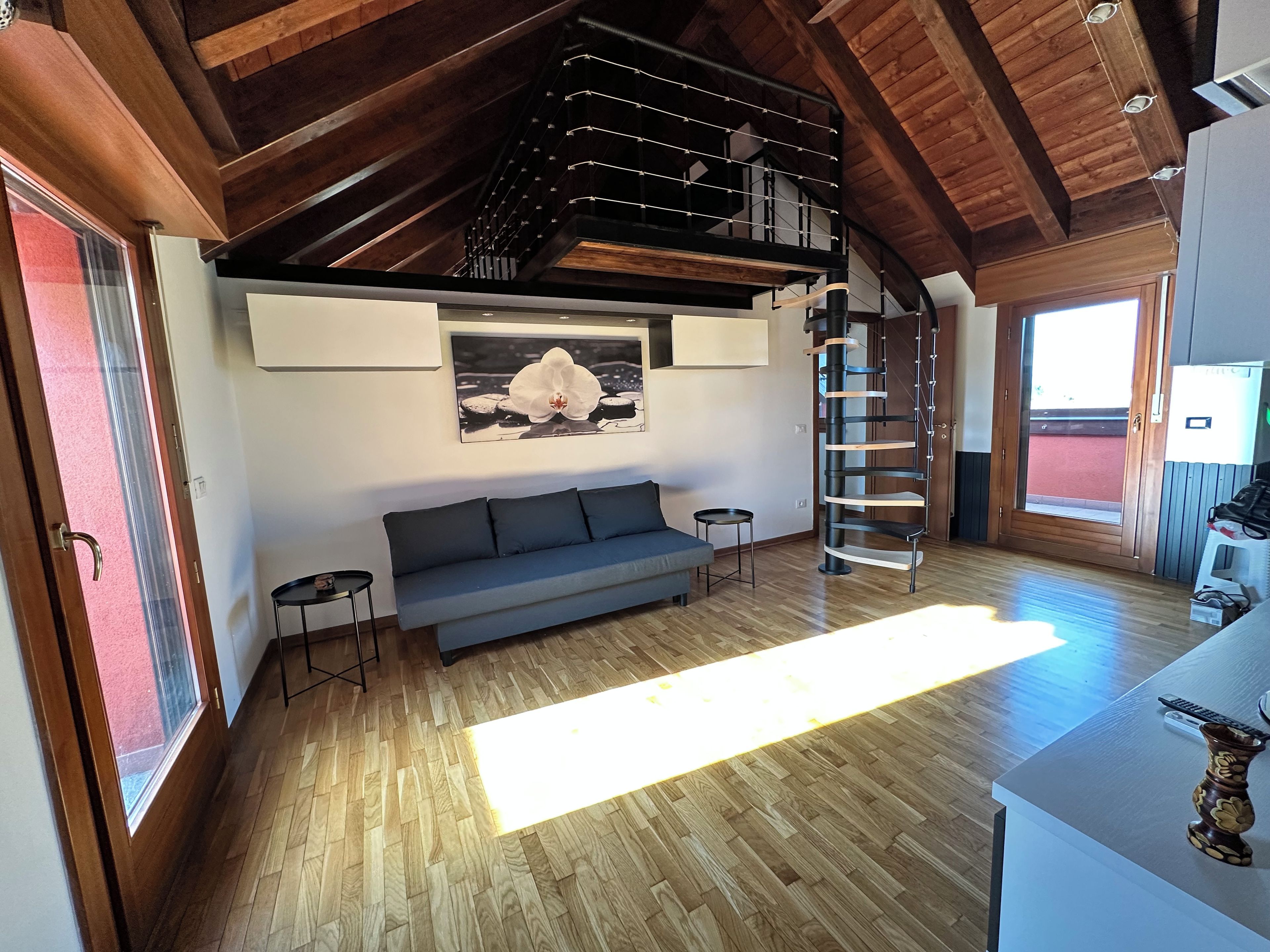 Una sala de estar moderna con techo de madera, un sofá, una mesita y una escalera.