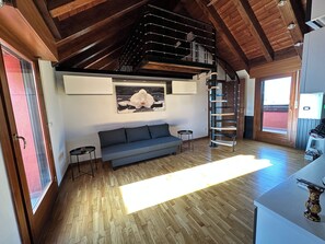 A modern living room with a wooden ceiling, a sofa, a small table, and a staircase.
