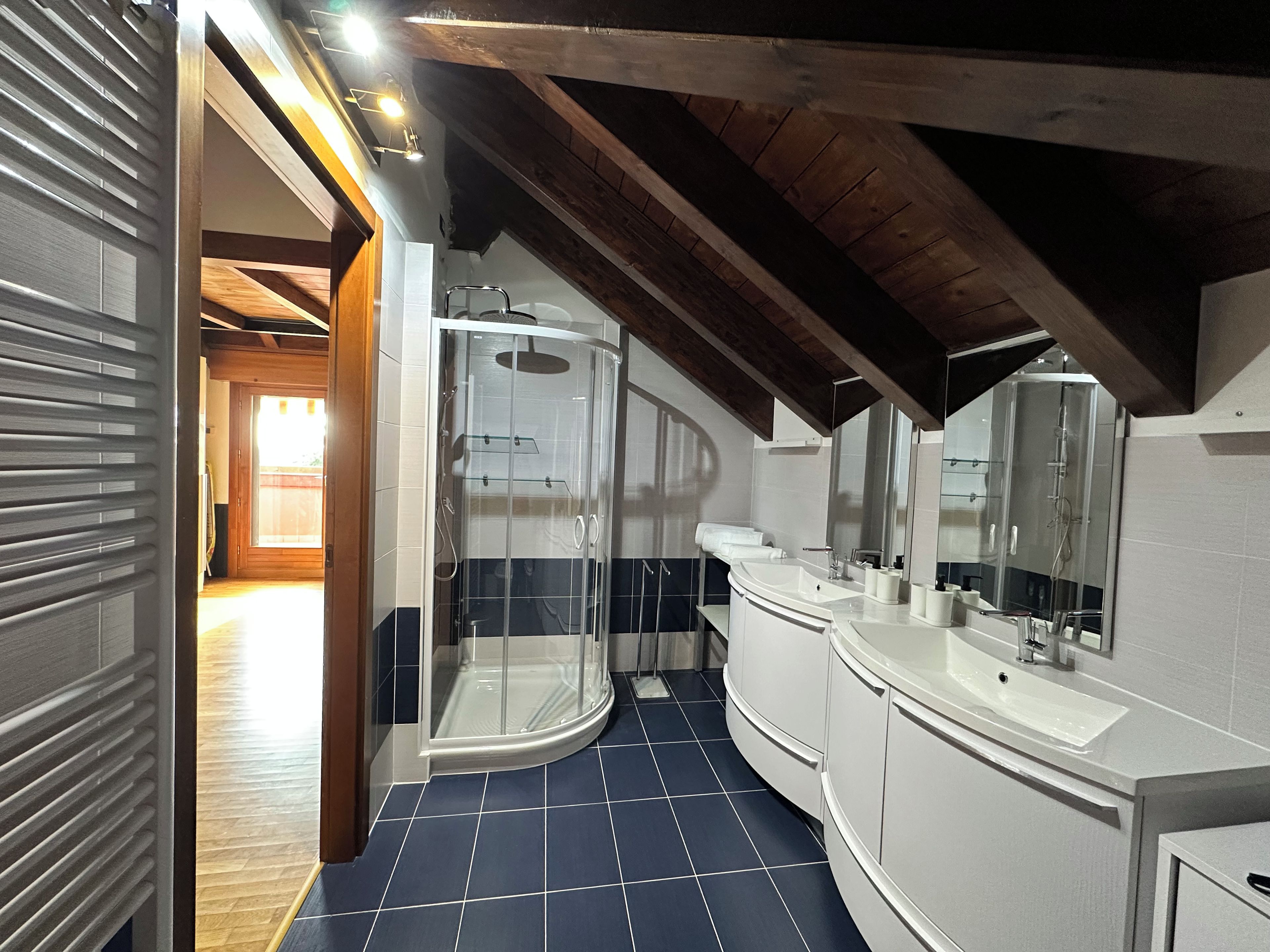 Un bagno moderno con cabina doccia in vetro, mobile lavabo bianco e un grande specchio.