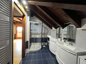 Een moderne badkamer met een douchecabine van glas, een witte wastafel en een grote spiegel.