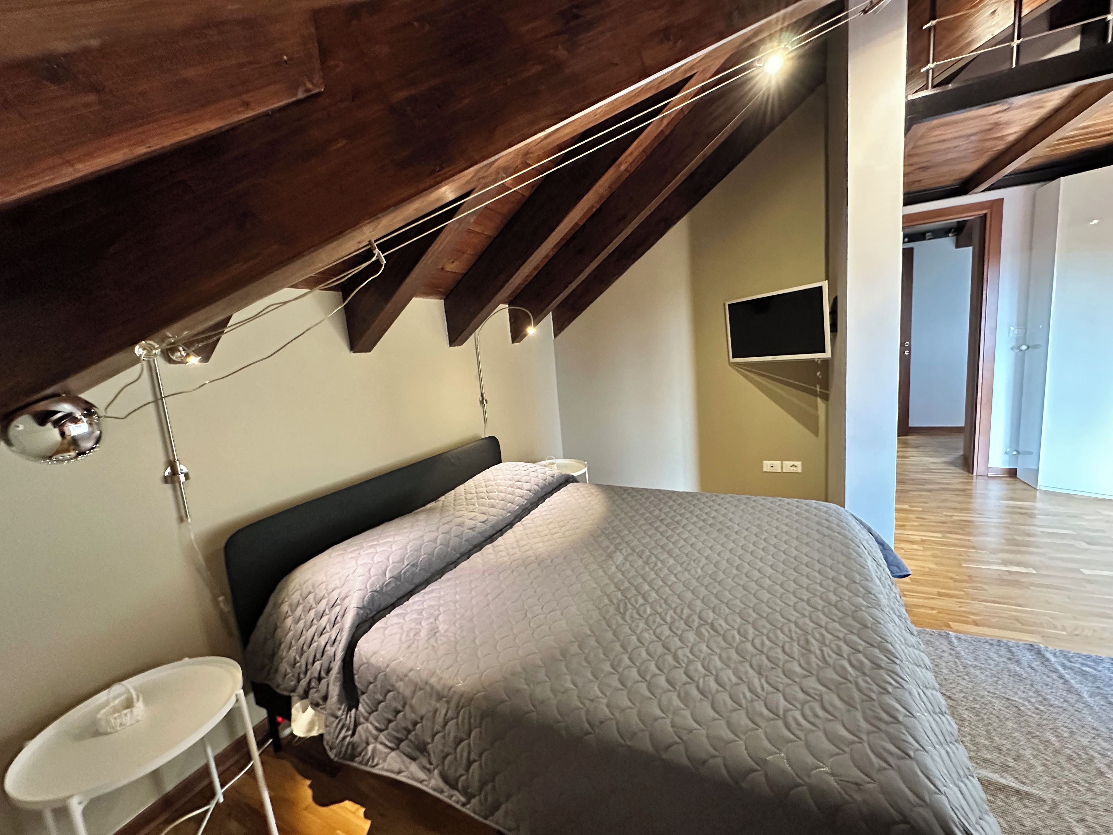 Une chambre à coucher avec un lit, une table de chevet, une lampe et un téléviseur fixé au mur.