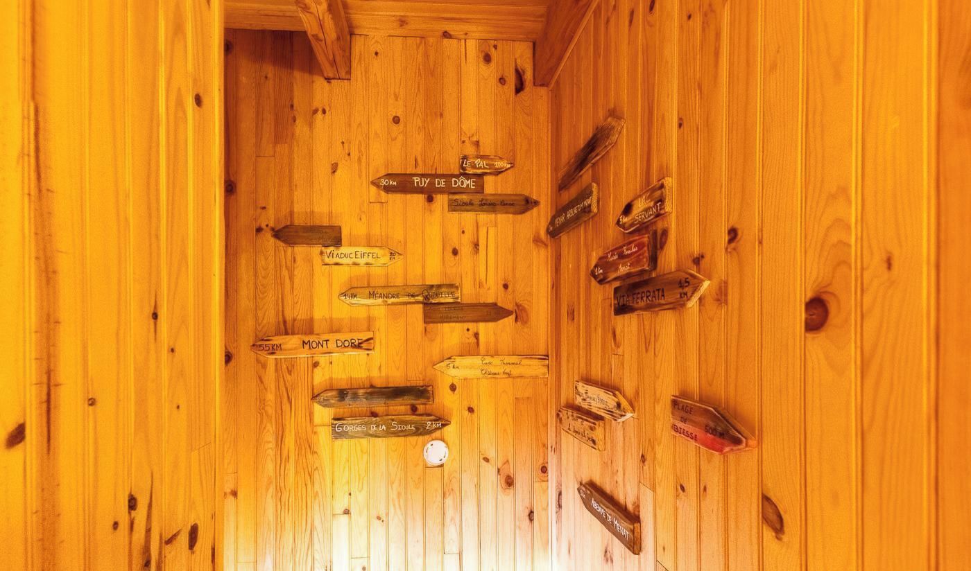 A wooden interior with directional signs pointing to various destinations.