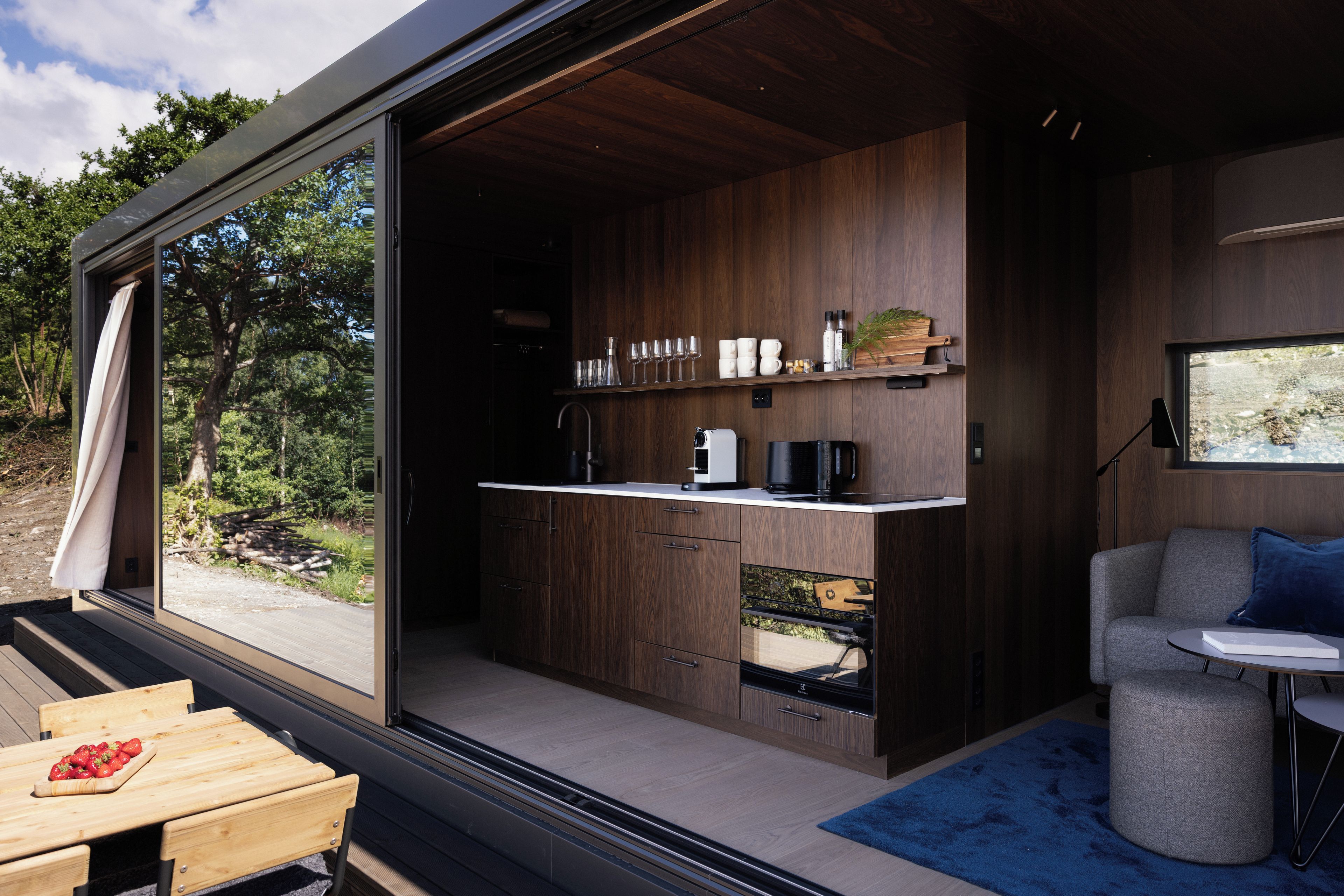 Una cocina moderna con un ventanal grande, armarios de madera y un comedor con mesa y sillas.