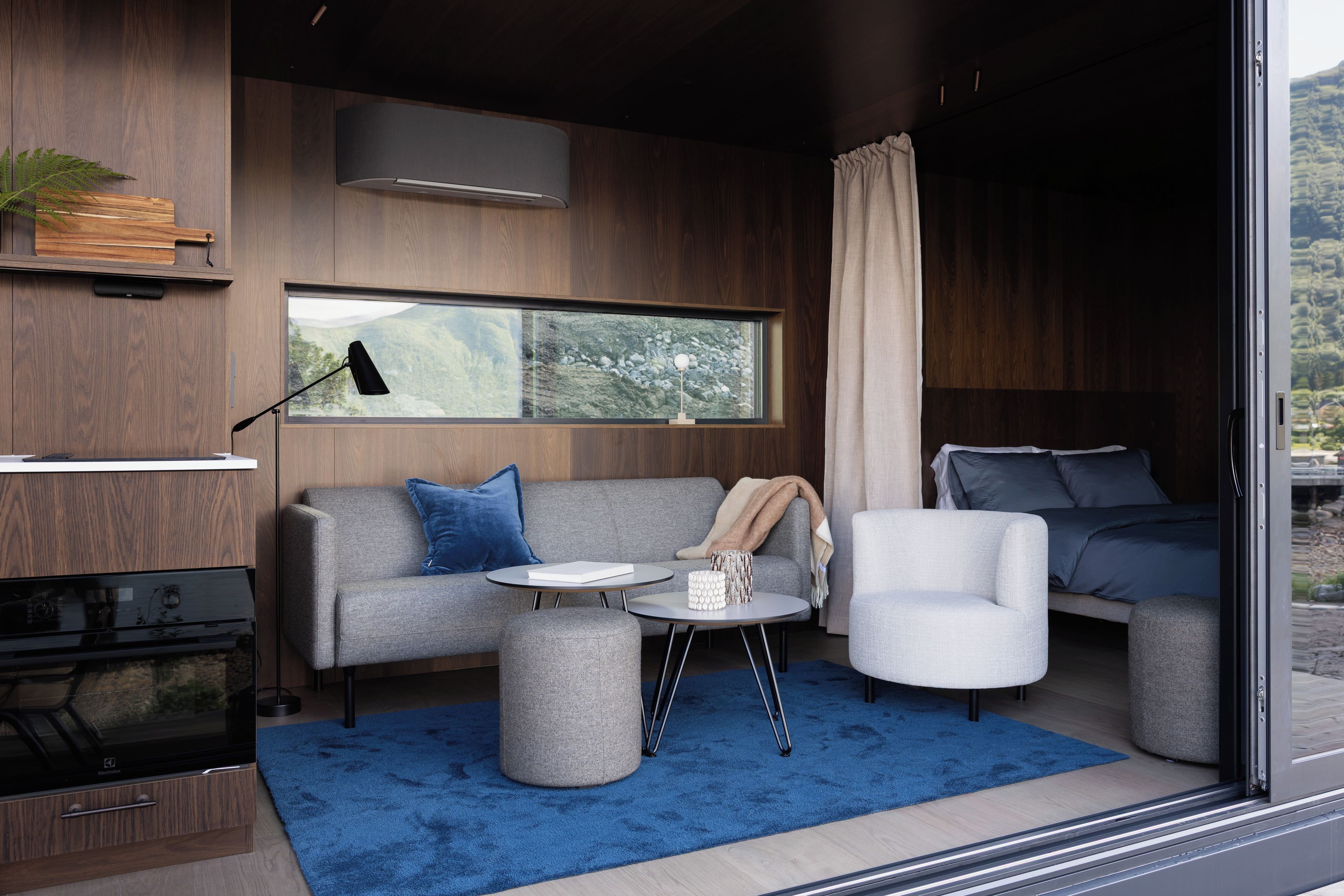 Una sala de estar moderna con sofá, sillón, mesa de centro y un amplio ventanal con vistas.