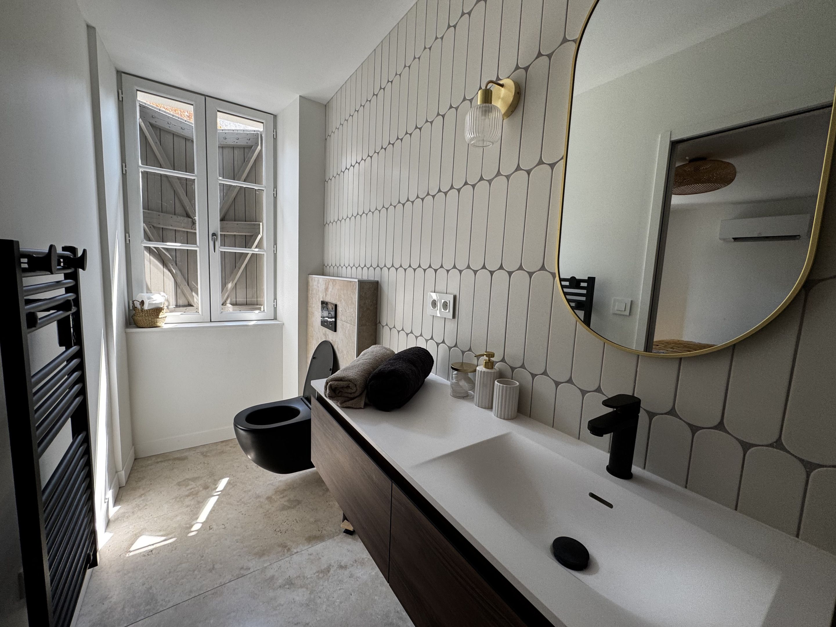 Un baño moderno con un espejo grande, un lavabo blanco y una ventana.