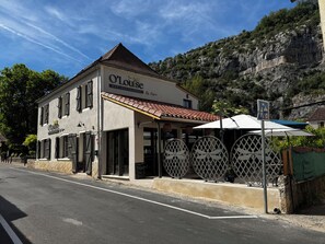 Un edifici amb un rètol que diu 'O'Louise Bar Restaurant' i terrassa exterior amb ombrelles.