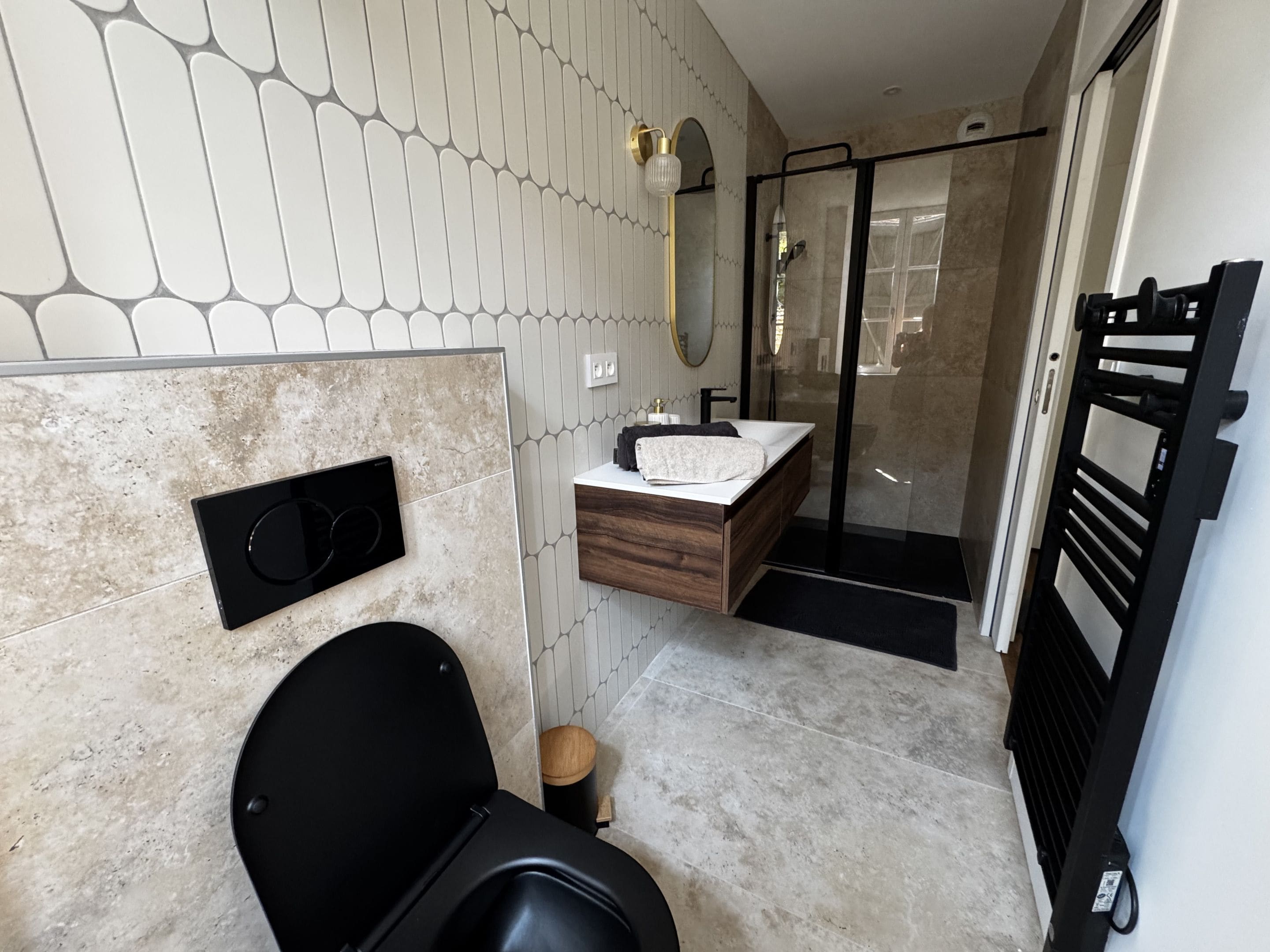 Ein modernes Badezimmer mit Toilette, einem Waschbecken mit Holzschublade und einer Dusche mit Glastüren sowie einem Handtuchhalter.