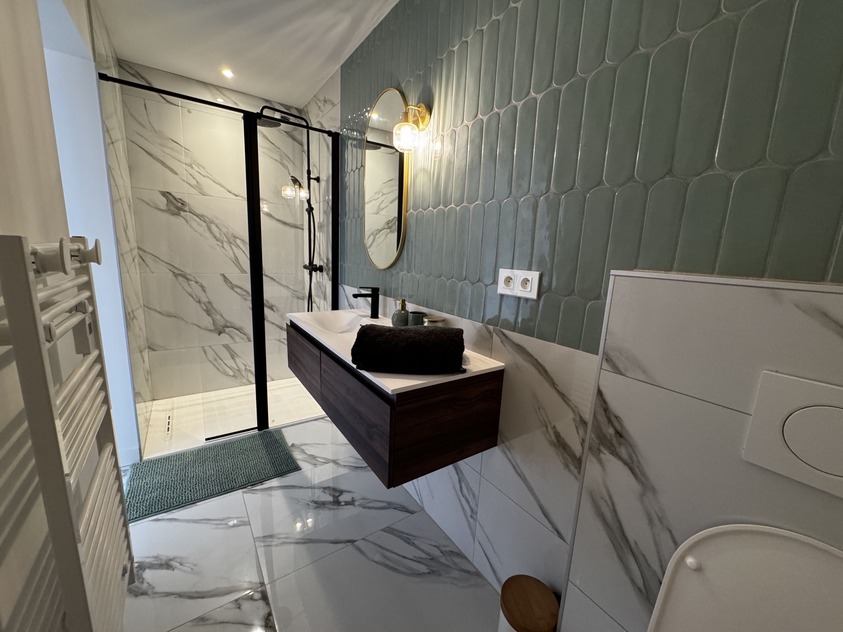 Een moderne badkamer met een douchecabine van glas, een betegelde vloer van marmer en een wastafelmeubel met een kastje van donker hout.