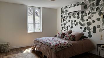 Un dormitorio con cama, ventana, aire acondicionado de pared y pared con diseño.