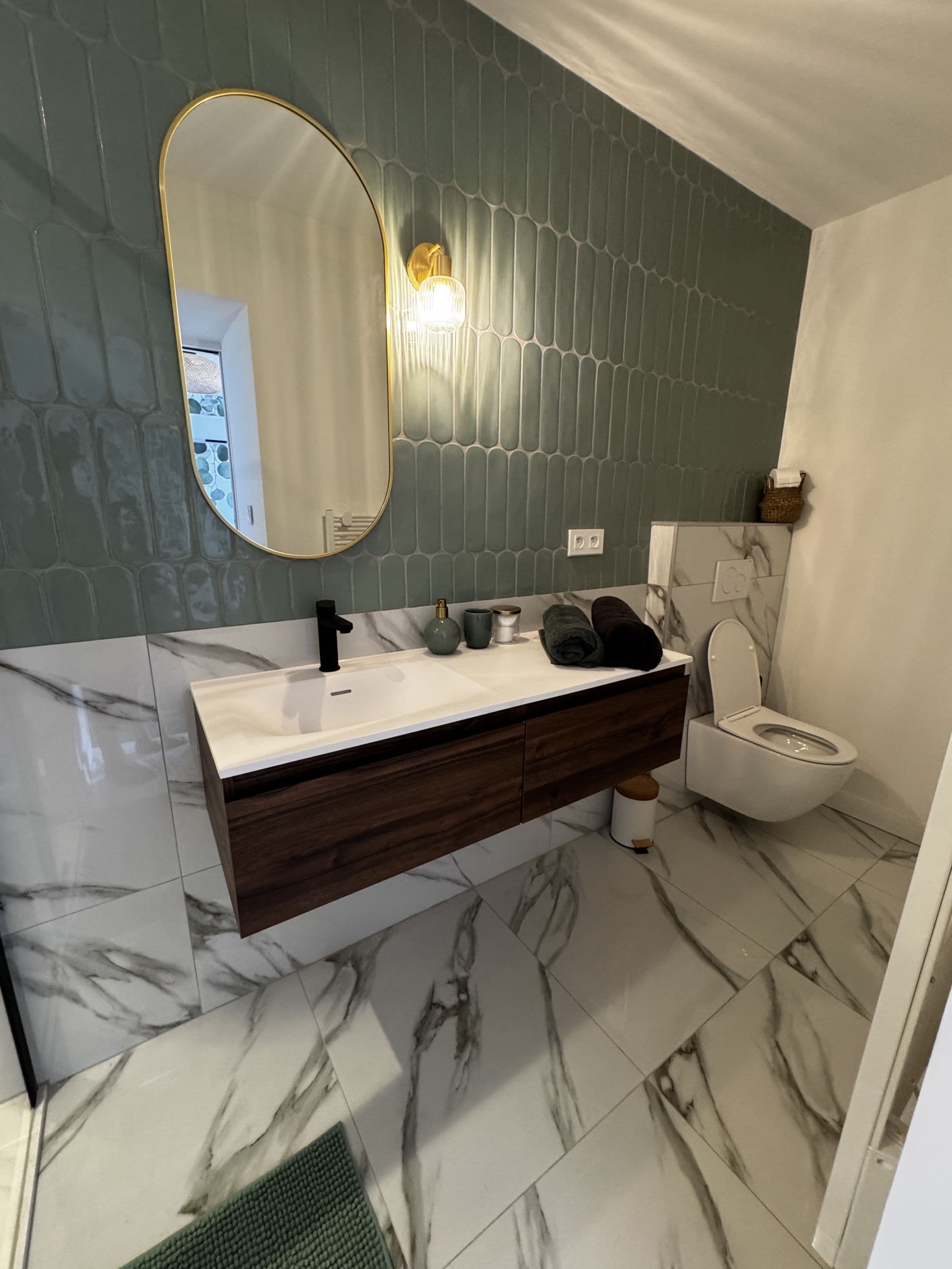 A bathroom with a marble sink, a toilet, and a mirror with a gold frame.