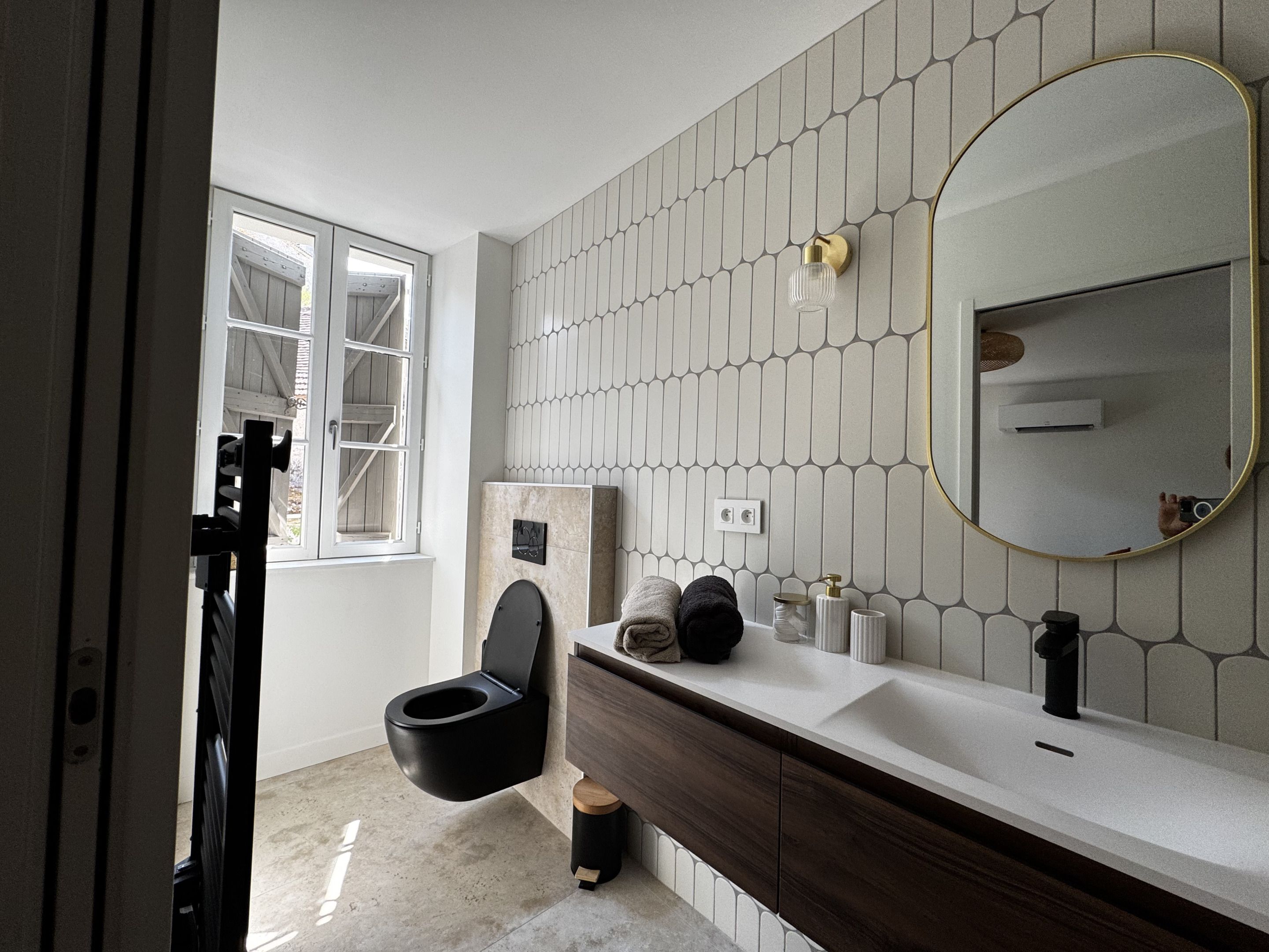 A modern bathroom with a toilet, vanity, and a large mirror.