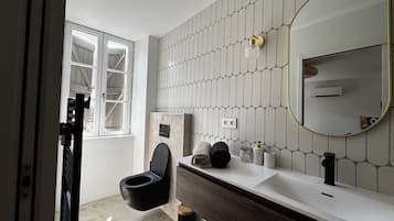 A modern bathroom with a toilet, vanity, and a large mirror.