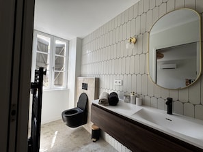 A modern bathroom with a toilet, vanity, and a large mirror.