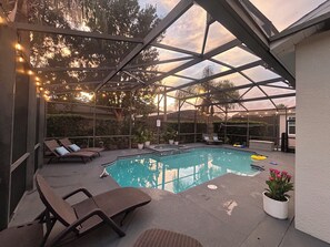 A covered outdoor swimming pool with lounge chairs and potted plants. - Luxury Spacious 6-Bedroom Pool Home Near Disney Sleeps 18 (Haines City)