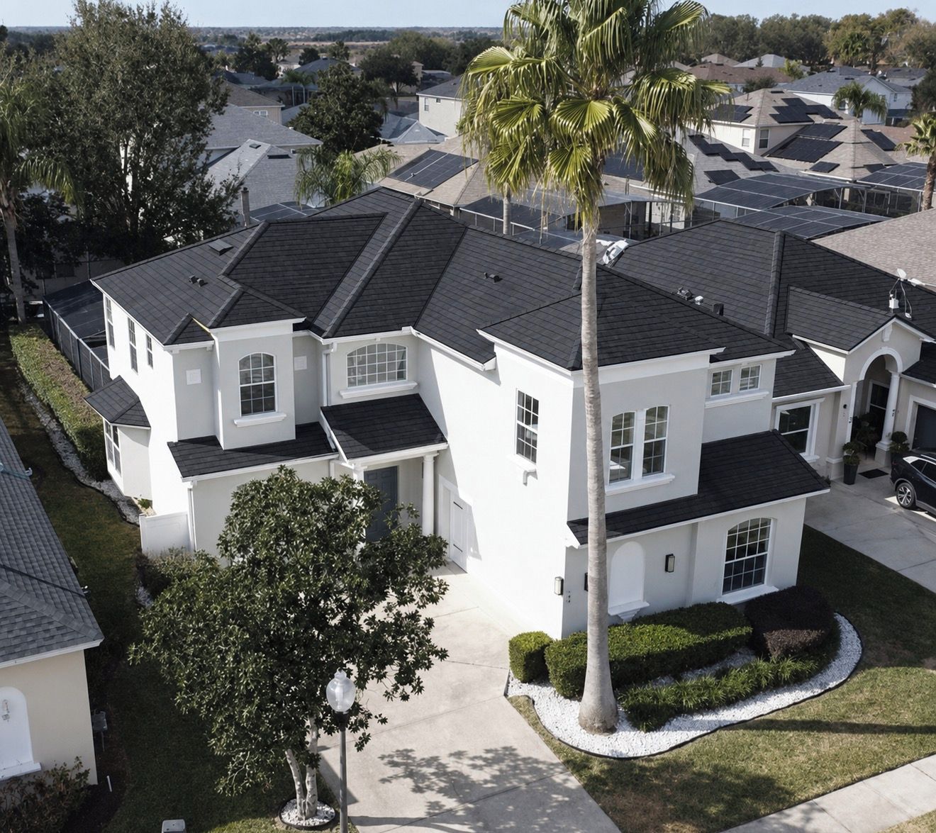 Un quartier résidentiel composé de plusieurs maisons, chacune présentant un style architectural distinct, notamment une grande maison blanche avec un arbre imposant devant.