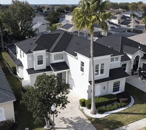 A residential area with multiple houses, each featuring a distinct architectural style, including a prominent white house with a large tree in front. - Luxury Spacious 6-Bedroom Pool Home Near Disney Sleeps 18 (Haines City)