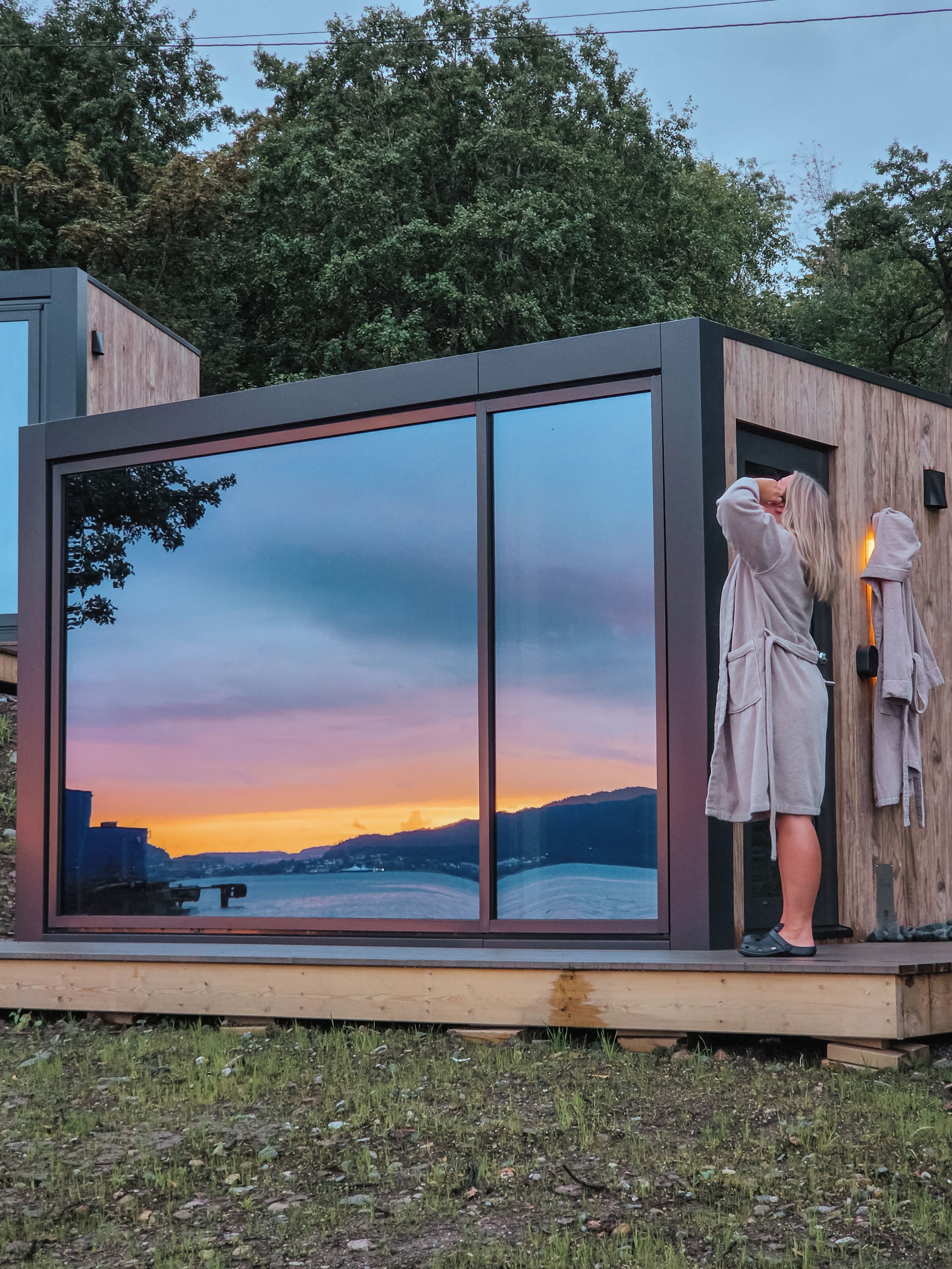 Eine moderne, gläserne Struktur mit Blick auf einen Sonnenuntergang über dem Wasser.