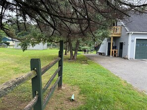 Une propriété résidentielle dotée d’une cour clôturée, d’un garage et d’une terrasse en bois.
