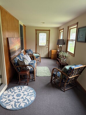 A living room with a sofa, two rocking chairs, a coffee table, a rug, a lamp, and a door with a window. - Serene 3-bedroom 3-full BR house with Heat in charming Manchester Center, VT. (Manchester)