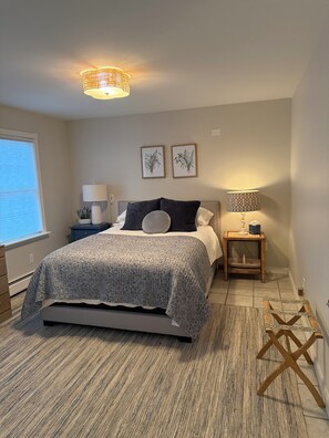 Une chambre à coucher avec un lit, des tables de chevet, une lampe et des œuvres d’art encadrées accrochées au mur.