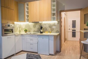 Een moderne keuken met witte kasten, een ingebouwde oven, een koffieapparaat en een kleine potplant.