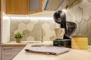 Une cuisine moderne équipée d’une machine à café intégrée, d’une bouilloire et d’un support pour la bouilloire sur le plan de travail.
