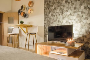 Une chambre moderne avec un bureau en bois, un téléviseur et un mur orné d’un motif hexagonal.