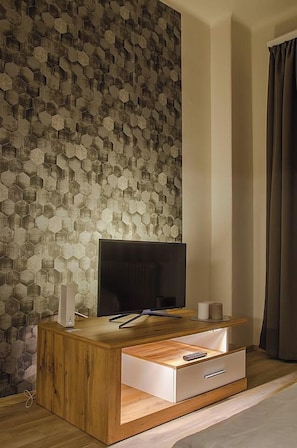 A modern living room with a wooden entertainment unit, a flat-screen TV, and a hexagonal patterned wall. - Hexagon Apartment Budapest (Budapest)