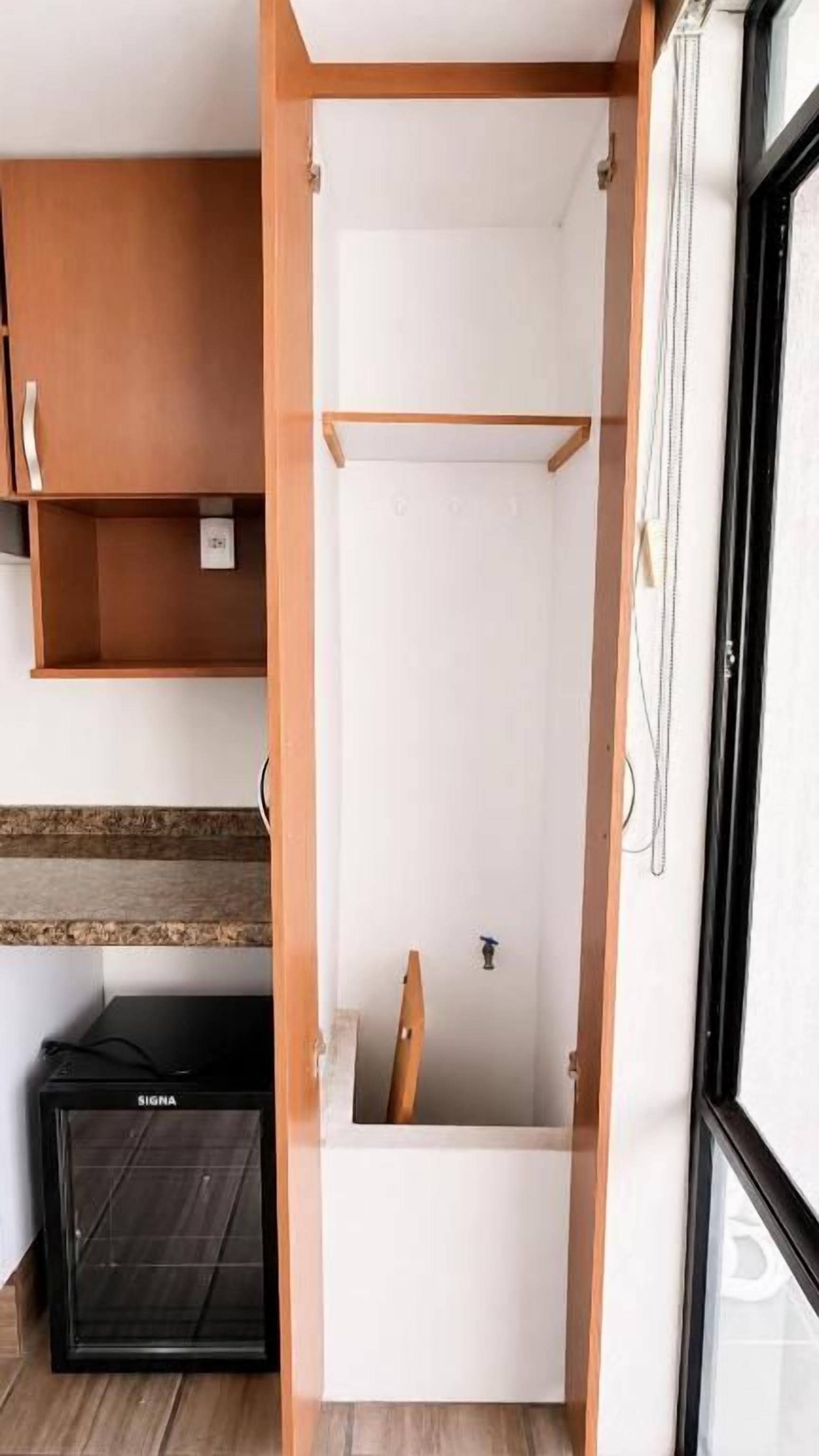 A narrow, enclosed space with a wooden interior and a white door, possibly a closet or storage area.