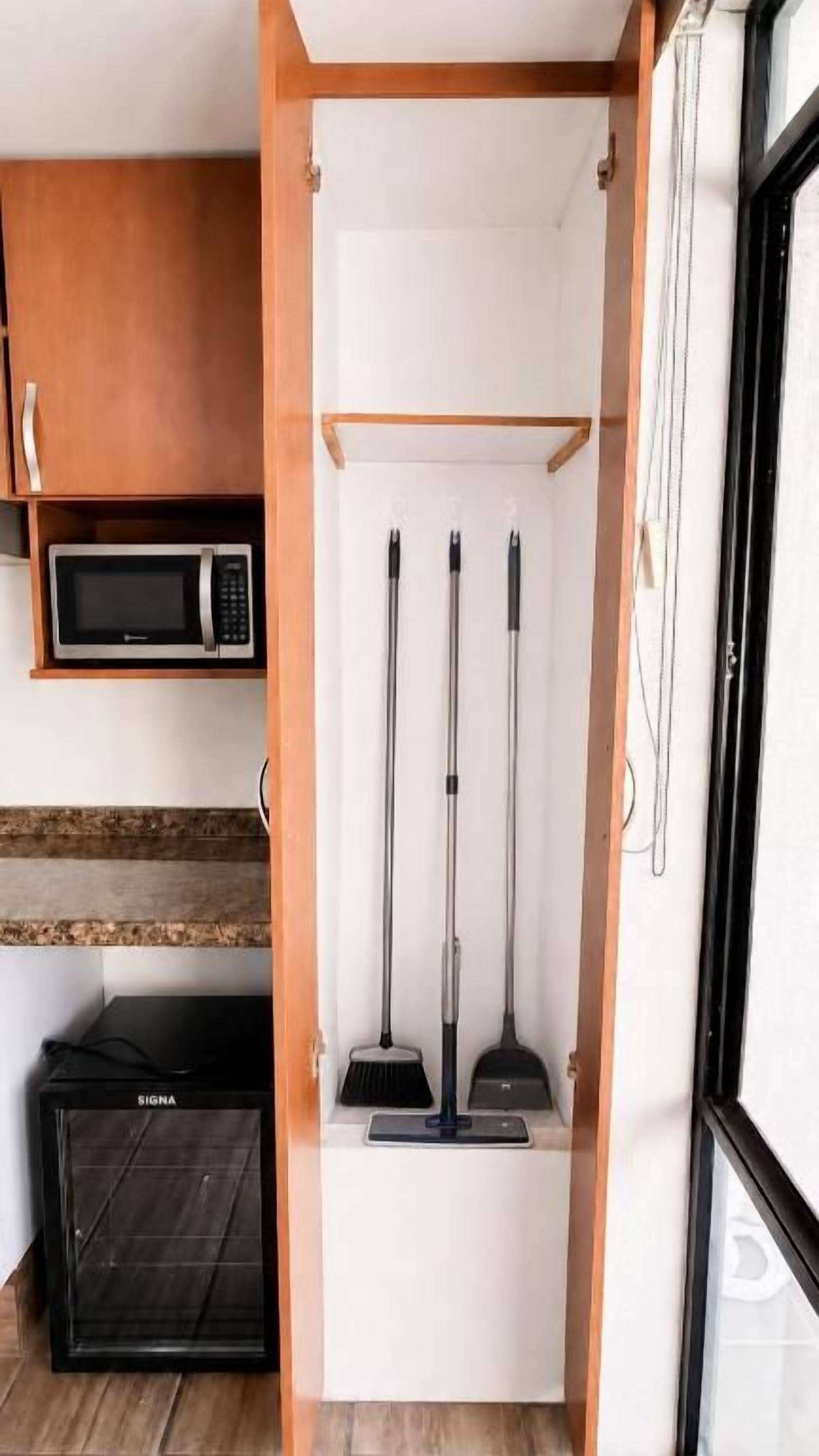 A kitchen with a microwave, oven, and a wooden cabinet.