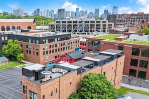 A multi-story building with a rooftop terrace, surrounded by other buildings and a city skyline. - Rooftop skyline views, walkable WeHo house, sleeps 10 near Geodis Park (Nashville)