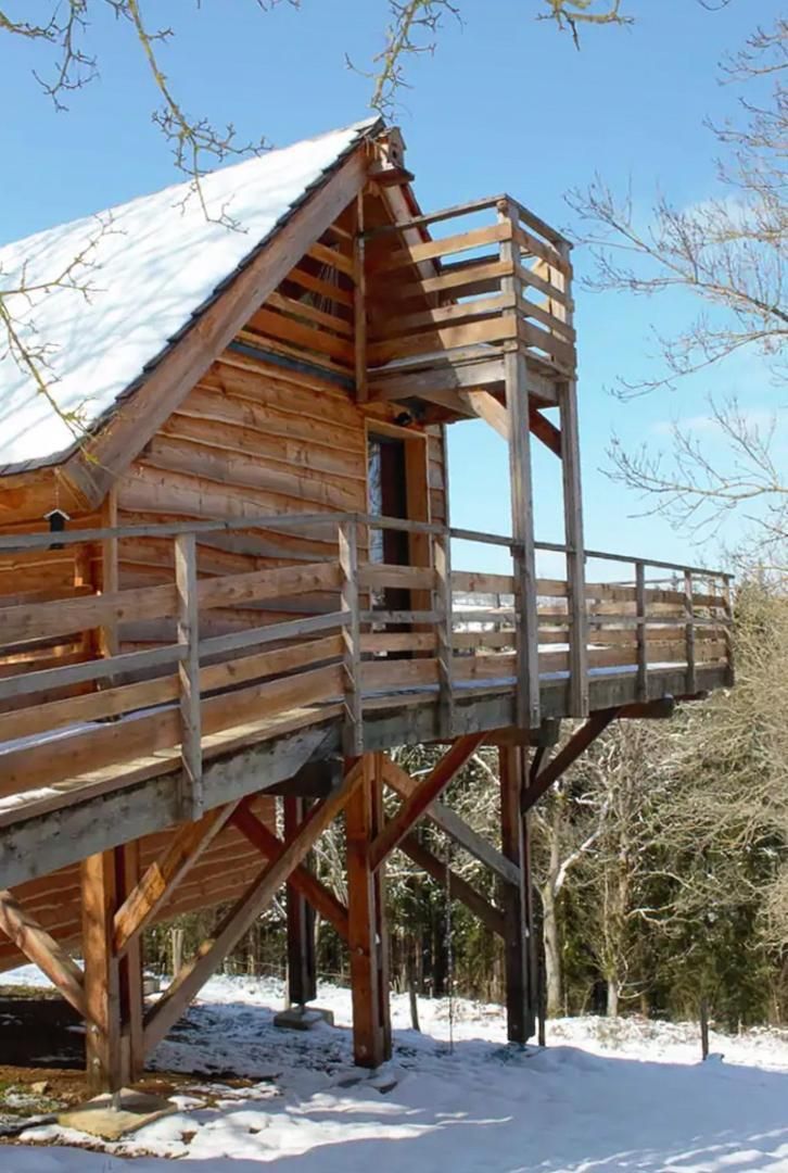 Eine Holzhütte mit Balkon, umgeben von Schnee und Bäumen.