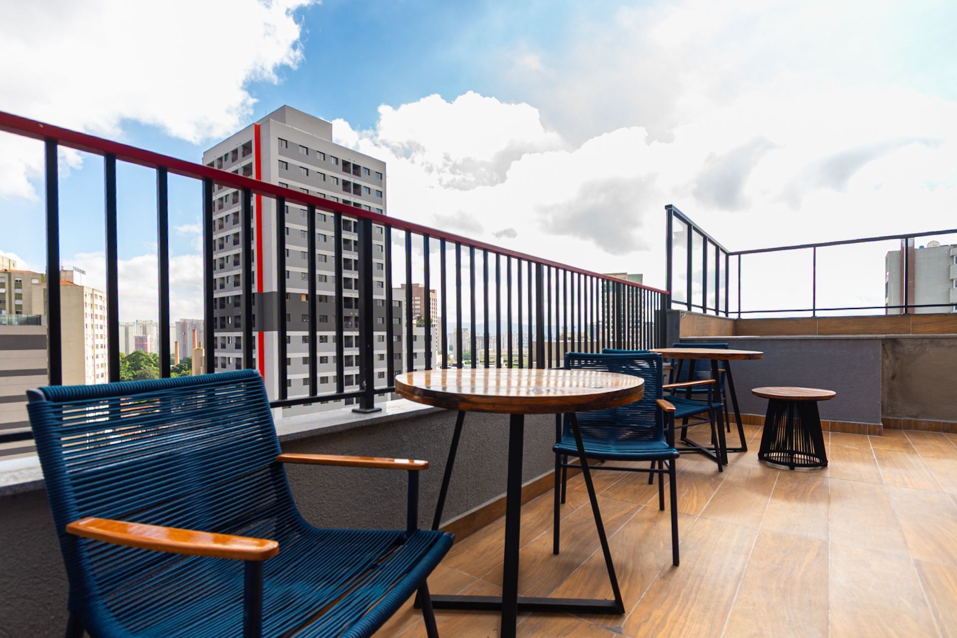 En takterrass med utomhusmöbler, utsikt över en stadssiluett och en modern byggnad i bakgrunden.