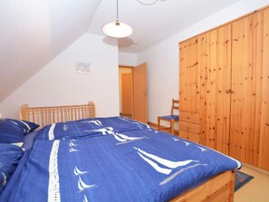 A bedroom with a bed, a wooden wardrobe, and a ceiling light. - Wunderschönes Appartement in Büsum mit Grill by Interhome (Büsum)