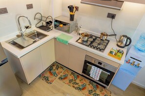 Eine kleine Küche mit Spüle, Herd, Backofen und Wasserspender.