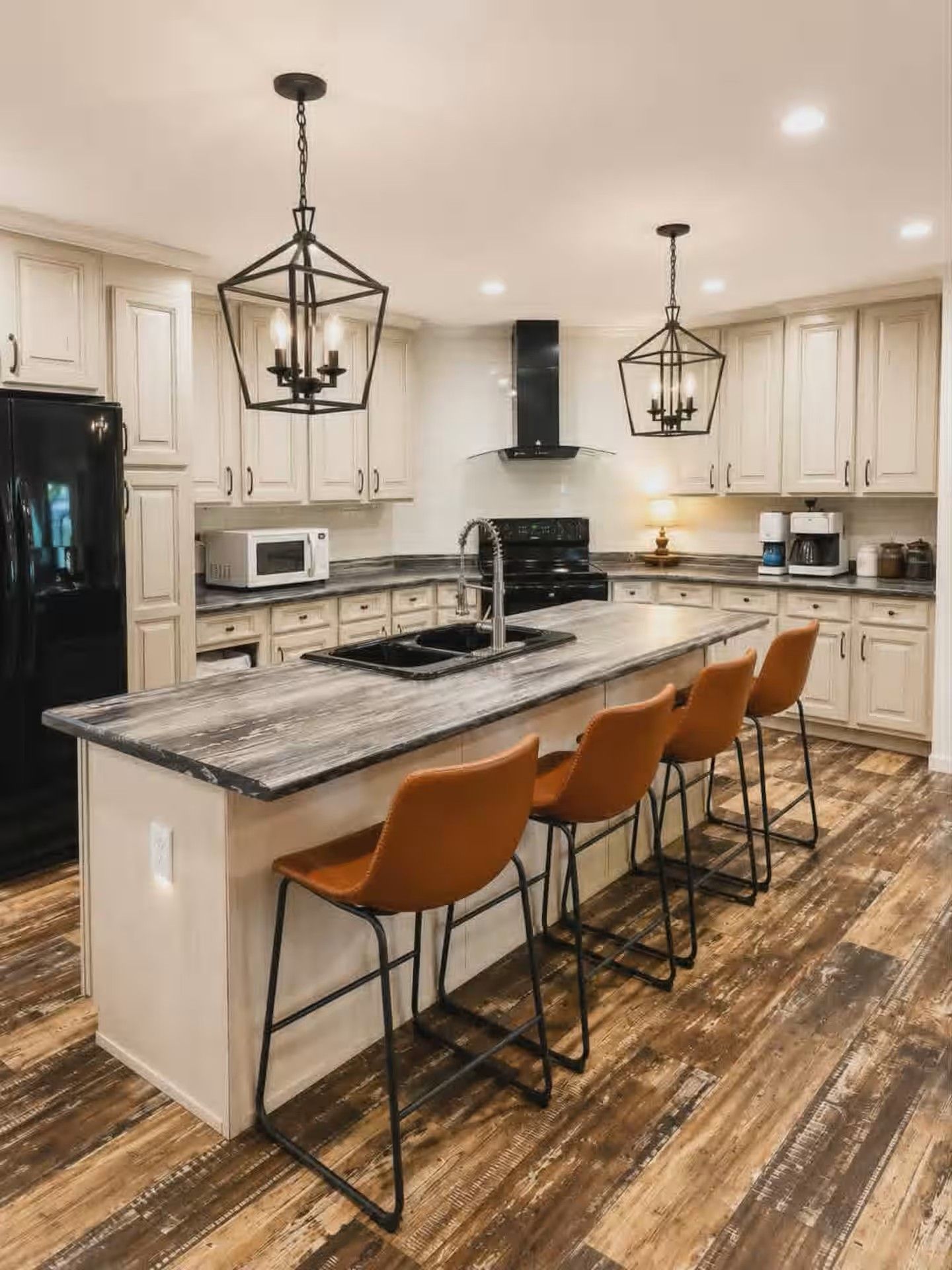 A modern kitchen with a central island, bar stools, and pendant lighting.
