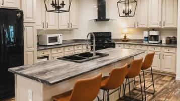 A modern kitchen with a central island, bar stools, and pendant lighting.