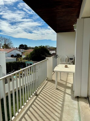 A balcony with a table and chairs, a white railing, and a view of houses and trees. - Royan - One-bedroom apartment for 4 people with a balcony and private parking, near the beaches and downtown (Royan)