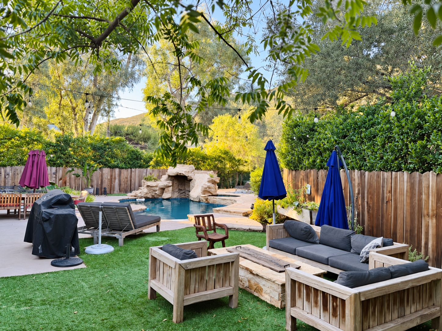 A backyard with a pool, wooden furniture, and a wooden fence.